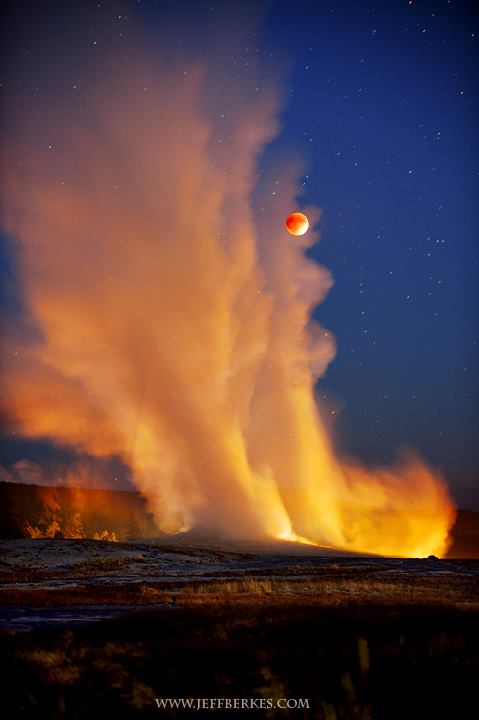Orange eclipsed moon peeking out behind tall column of steam and spray.