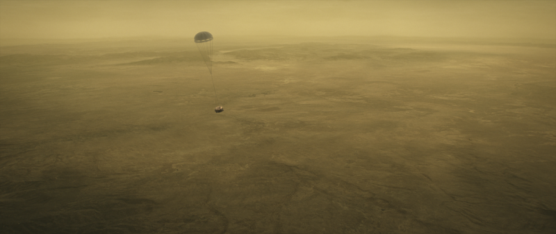 Small machine suspended from parachute in foggy atmosphere above yellowish landscape.