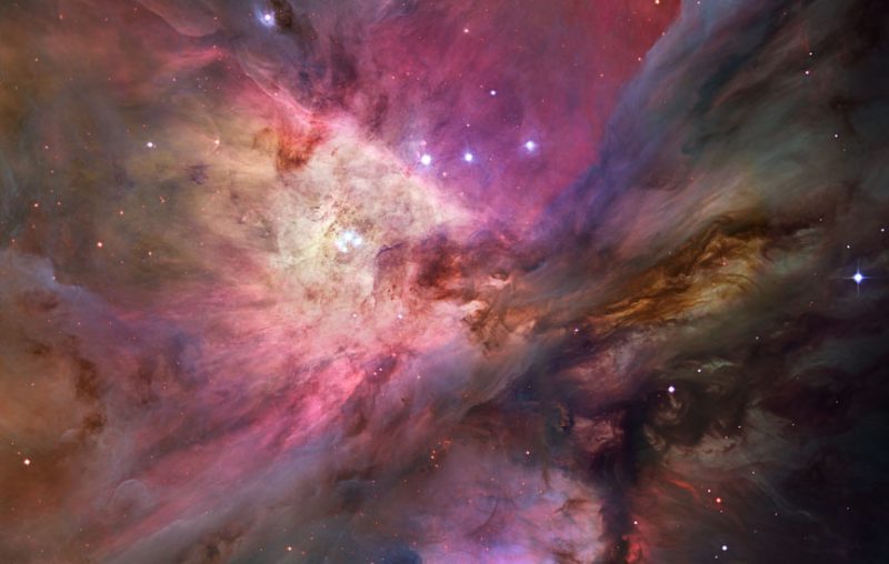 Colorful Orion Nebula cloud with scattered stars in foreground.