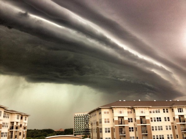Dramatic image of clouds like long horizontal cylinders over a 3-story building.