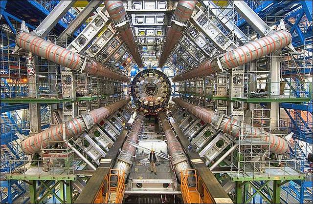 Huge machine, tiny person standing in it for scale, with giant radial pipes coming out from the center.