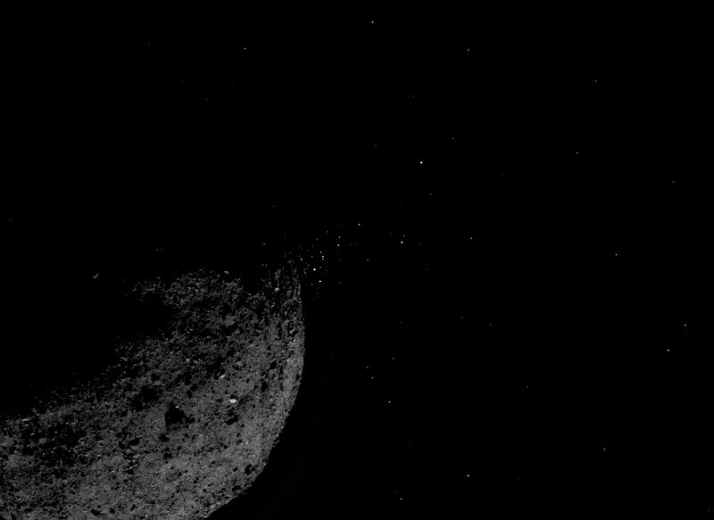 Crescent asteroid with array of tiny bright dots on one side.