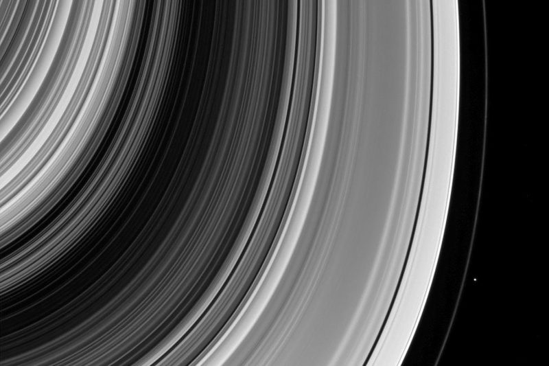 Very many rings of Saturn with a tiny dot outside the outermost visible one.