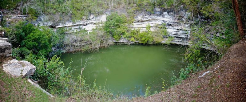 Round cliff-sided pool with green water on Earth.