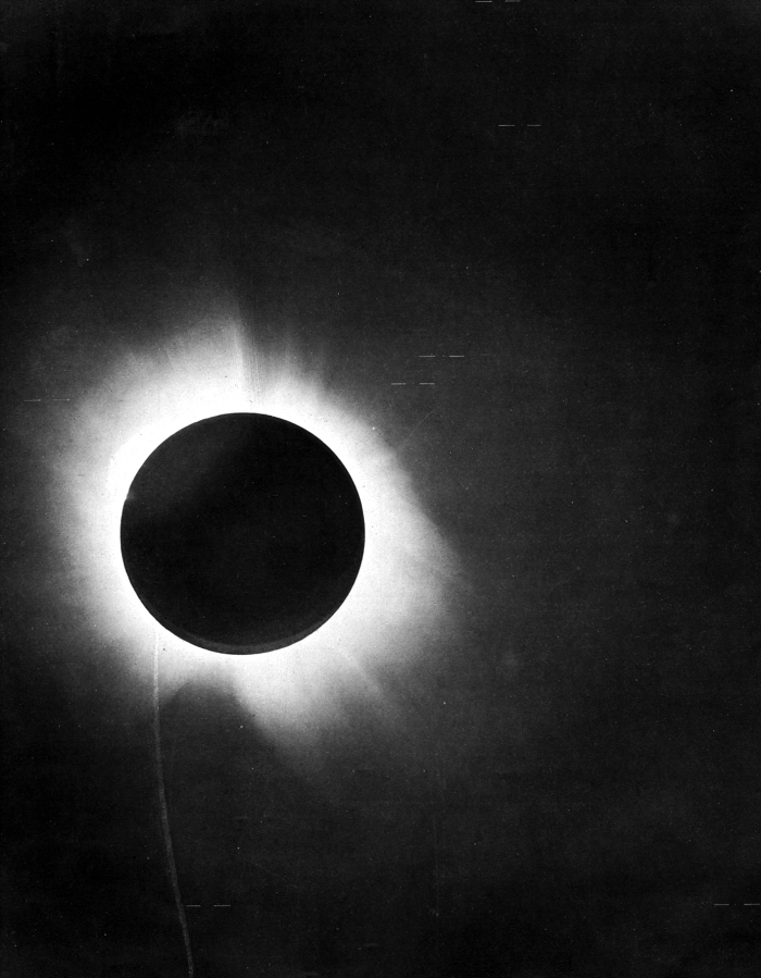 Black circular silhouette of new moon, surrounded by solar corona, during a total solar eclipse.