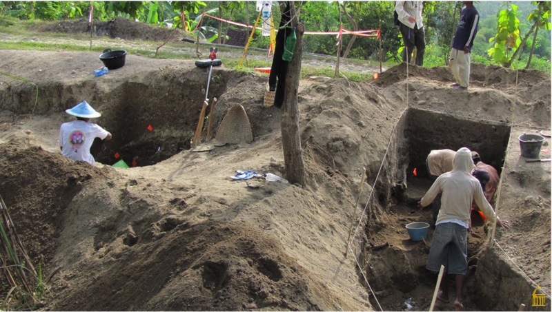 An excavation site, with several large holes in which men are digging.