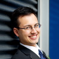 Smiling man in suit leaning against wall.